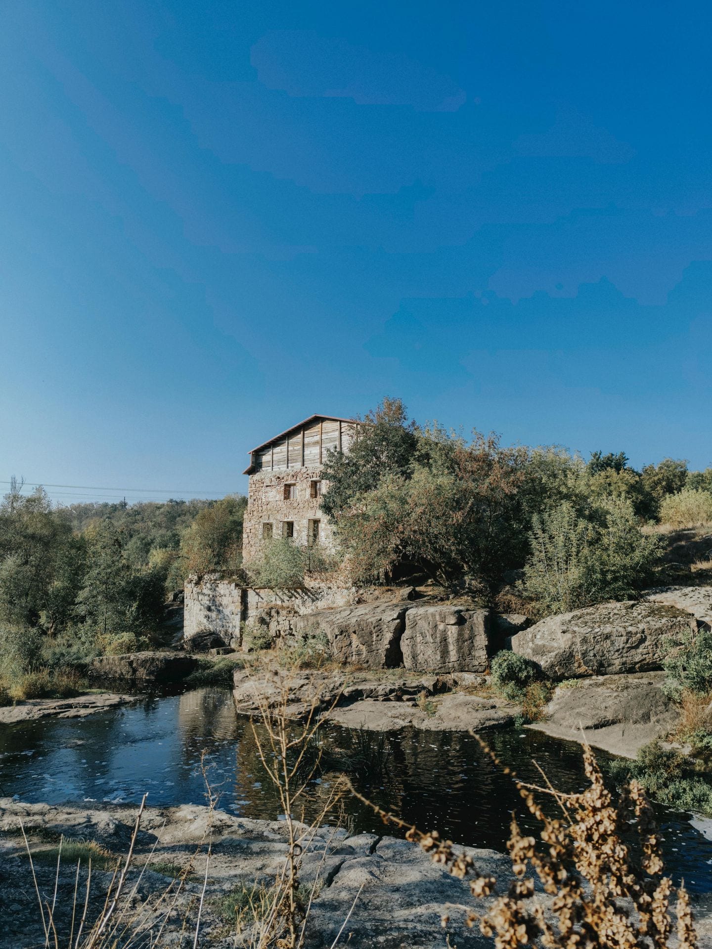 Casa tradicional em xisto junto a ribeiro em paisagem rural portuguesa
