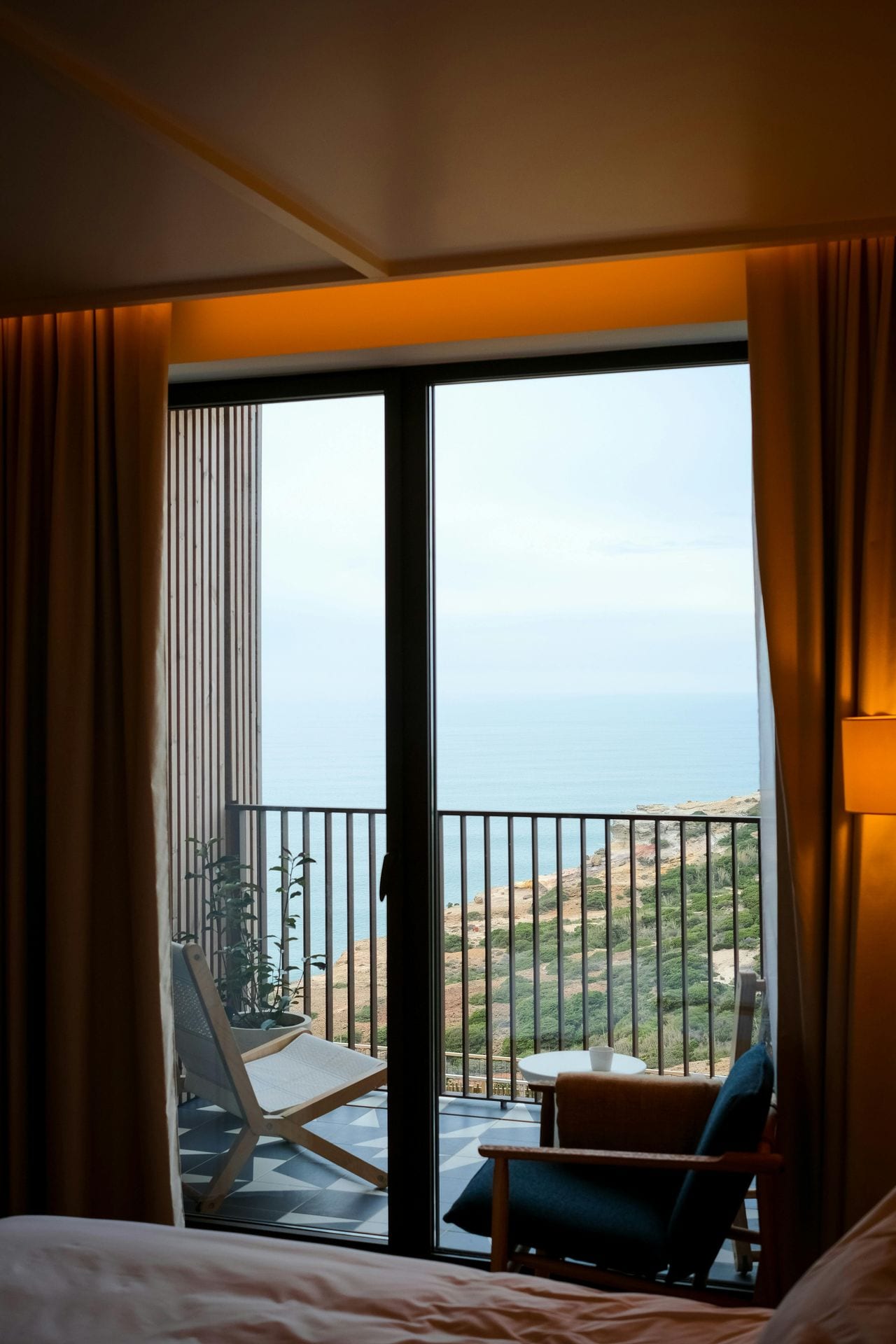 Quarto moderno com porta envidraçada aberta para varanda com vista de mar