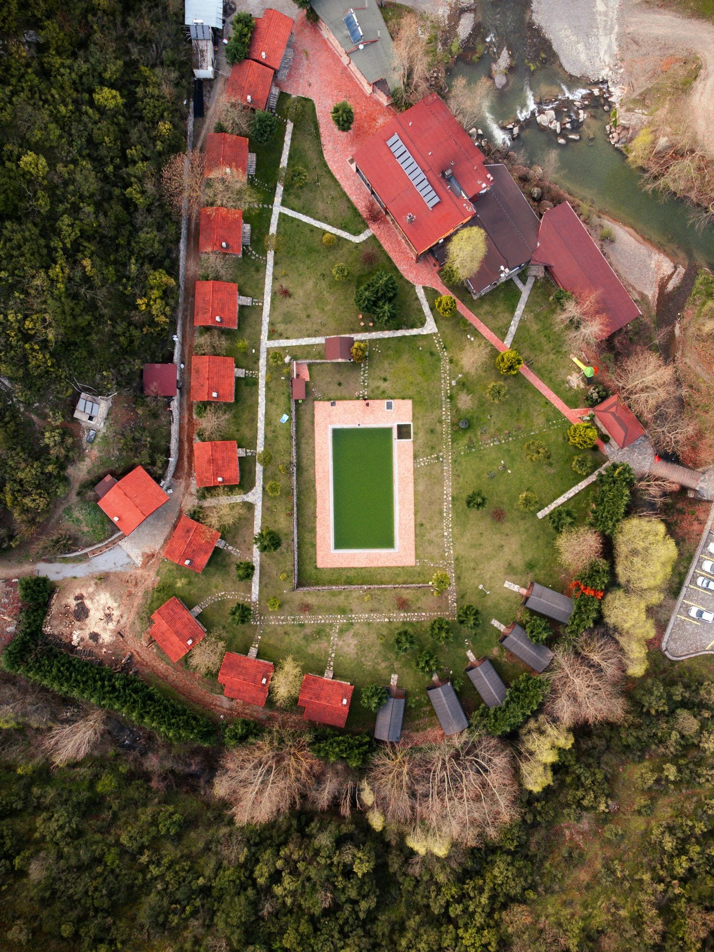 Vista aérea de pequeno empreendimento rural com piscina e chalés de telha vermelha