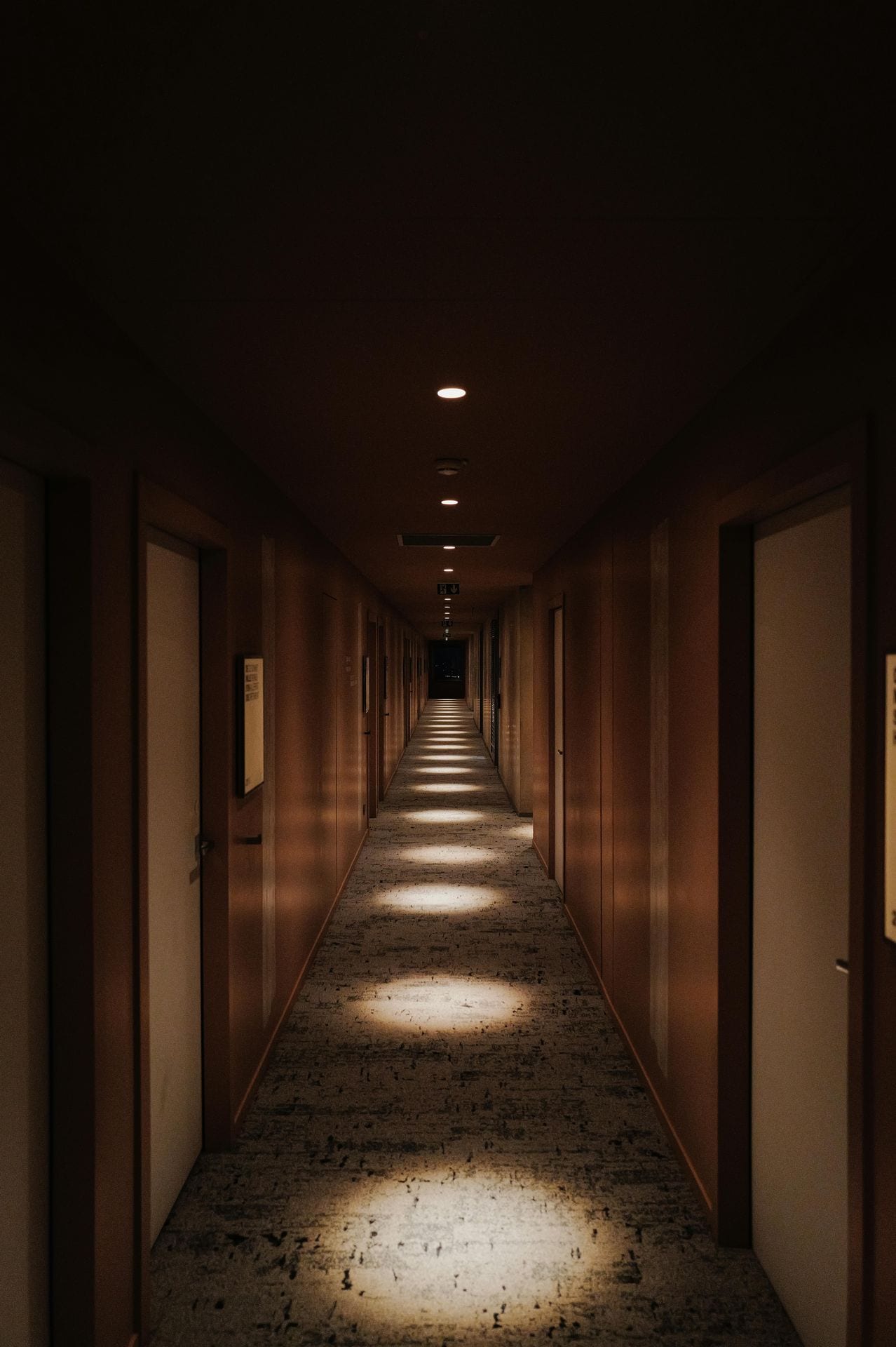 Corredor de hotel iluminado pela luz natural que entra do fundo — observação atenta