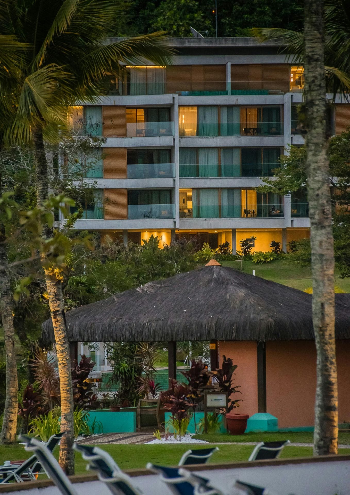 Edifício de empreendimento turístico junto à praia com palhota e palmeiras