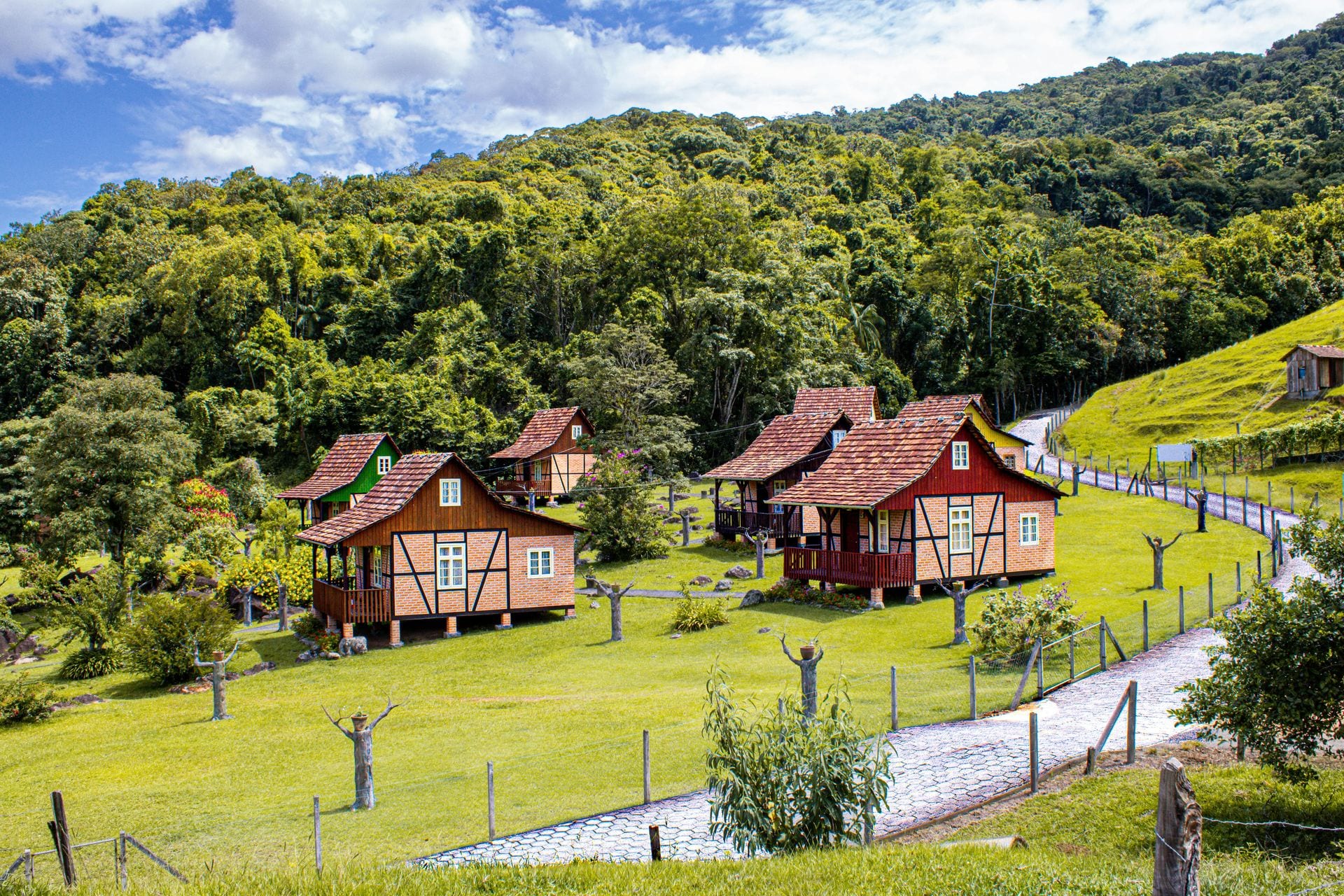 Conjunto de casas tradicionais em madeira pintada num vale verde — turismo rural
